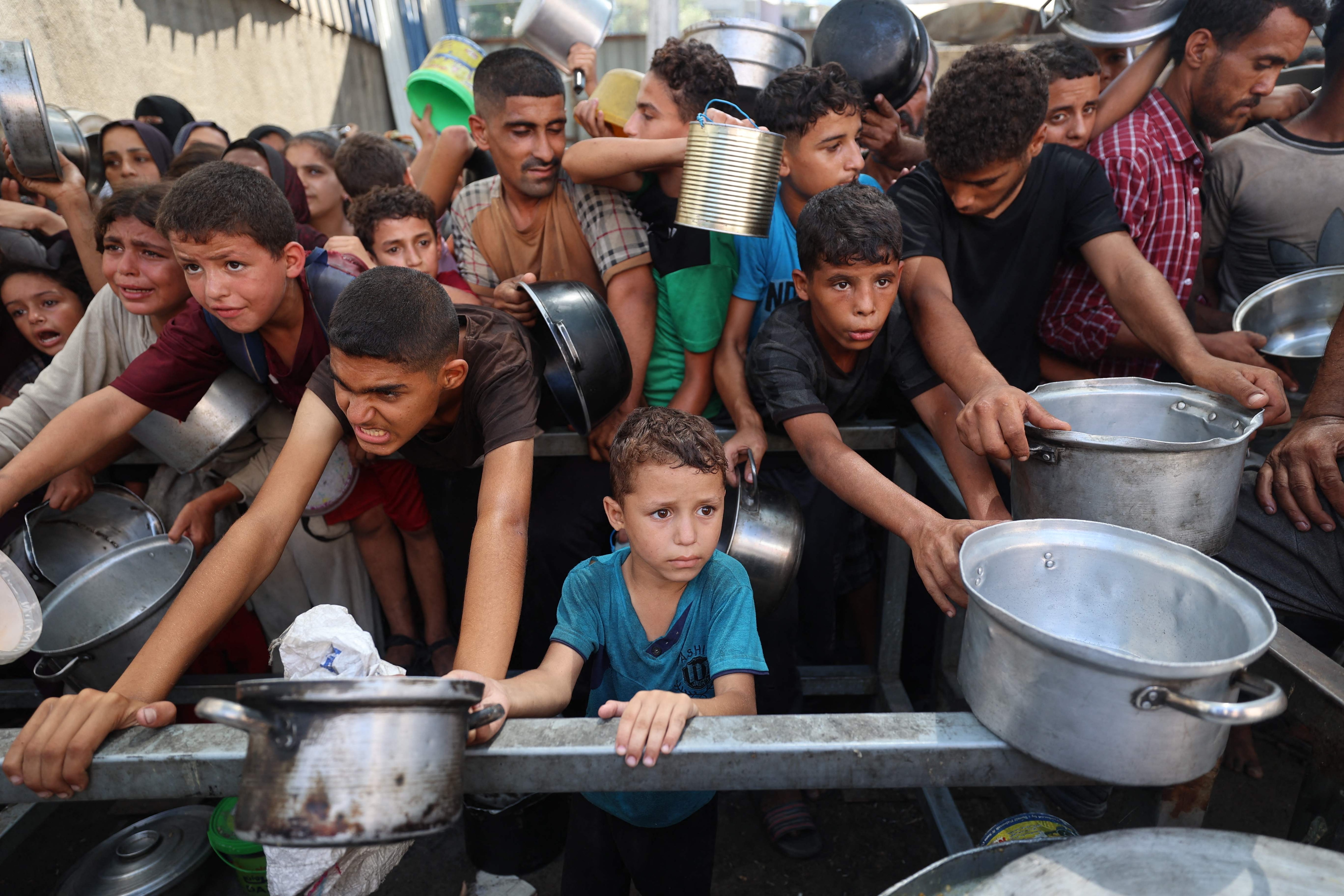 Palestinians queue to receive a hot meal from a charity kitchen in the Nuseirat refugee camp in the Israel-besieged Gaza Strip amid the famine crisis(AFP)